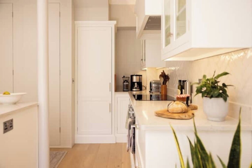 Een moderne keuken met witte kastjes, een aanrecht met een koffiezetapparaat en een plant.