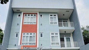A two-story building with a red and grey facade, multiple windows, and a balcony. - OYO 1158 Kegama Residences 2 (Dasmariñas)