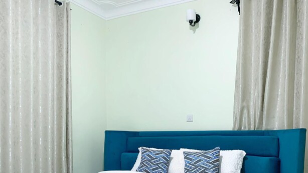 Een slaapkamer met een blauw bed, wit beddengoed en een bijpassende blauwe bank.