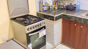 Een kleine keuken met een gasfornuis, oven en een koelkast.