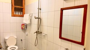Een badkamer met toilet, douche, wastafel en een spiegel met houten lijst.