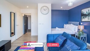 Ein modernes Schlafzimmer mit einem Bett, einem blauen Sofa, einer Chandelierleuchtre und einer Wanduhr.