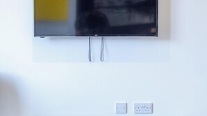 Ein Flachbildfernseher an der Wand über einer schwarzen Unterhaltungsecke mit zwei Steckdosen und einer Fernbedienung.