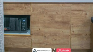 A kitchen with wooden cabinets, a microwave, a sink, and a trash bin. - Stylish Urban Studio in Sheffield –  APT 21 (Sheffield)