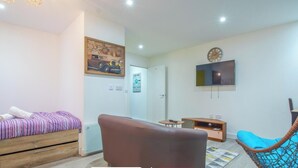 A modern apartment with a bed, a sofa, a TV, and a chair. - Stylish Urban Studio in Sheffield –  APT 21 (Sheffield)