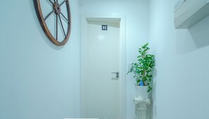 Un pasillo con una puerta señalizada para mujeres, una planta en maceta y un columnilla decorativa.