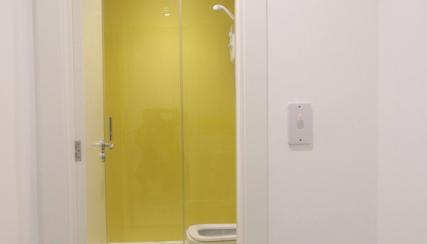 Ein Badezimmer mit einer gelben Tür, einer weißen Toilette und einer Duschkabine.