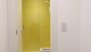 A bathroom with a yellow door, a white toilet, and a shower area.