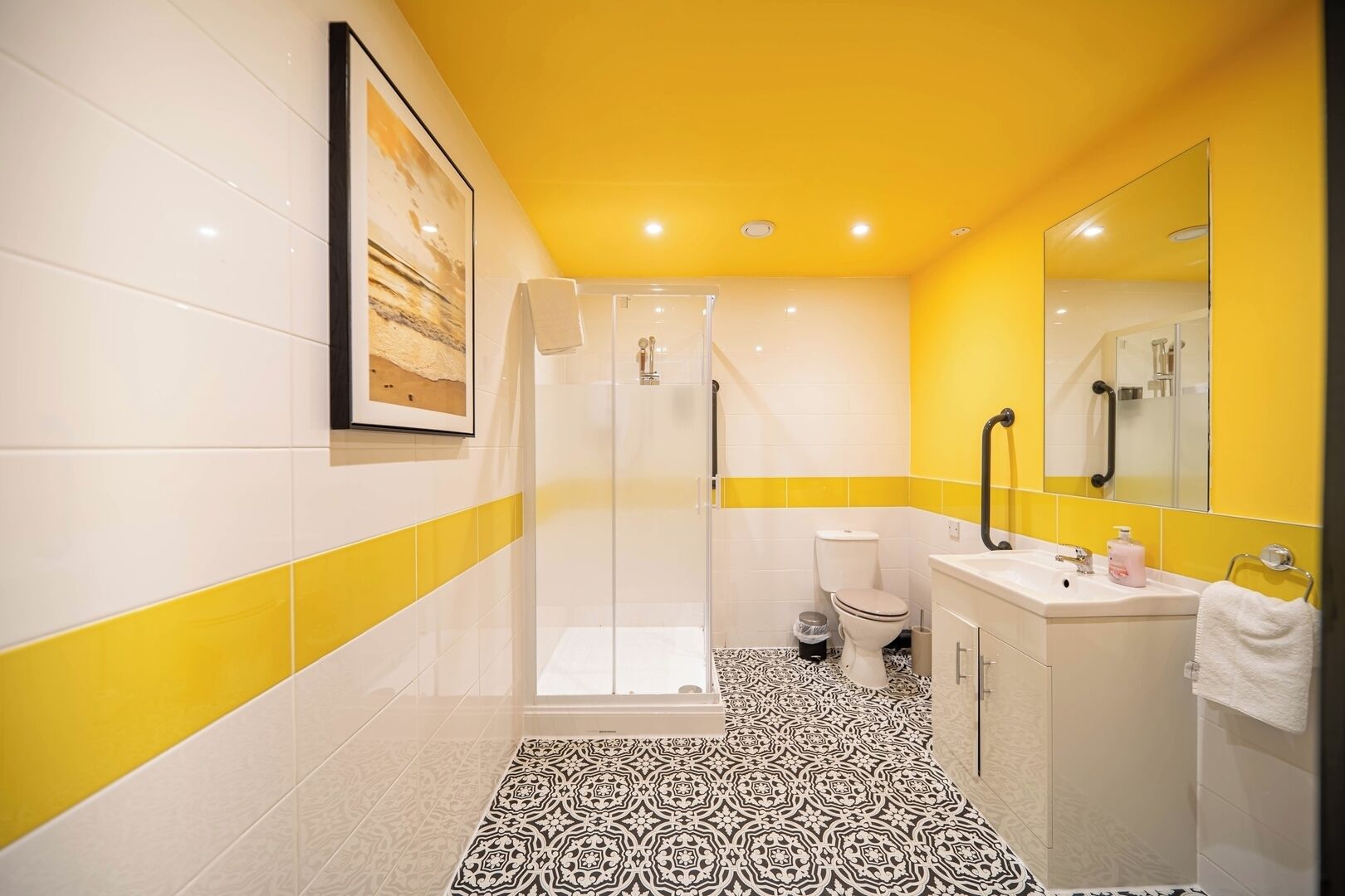 A bathroom with a glass shower enclosure, a white toilet, and a sink with a mirror.