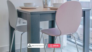 Un comedor moderno con una mesa, sillas, un jarrón con flores y vistas a la calle.