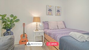 Un dormitorio con cama, una guitarra, una lámpara y una planta.