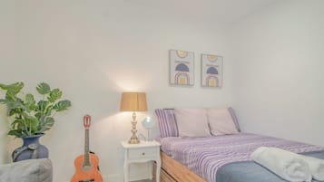 Ein Schlafzimmer mit einem Bett, einer Gitarre, einer Lampe und einer Pflanze.