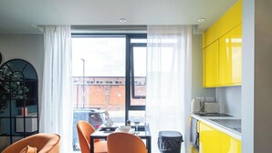 Un appartement moderne doté d’un coin repas, d’une cuisine jaune et de grandes fenêtres.