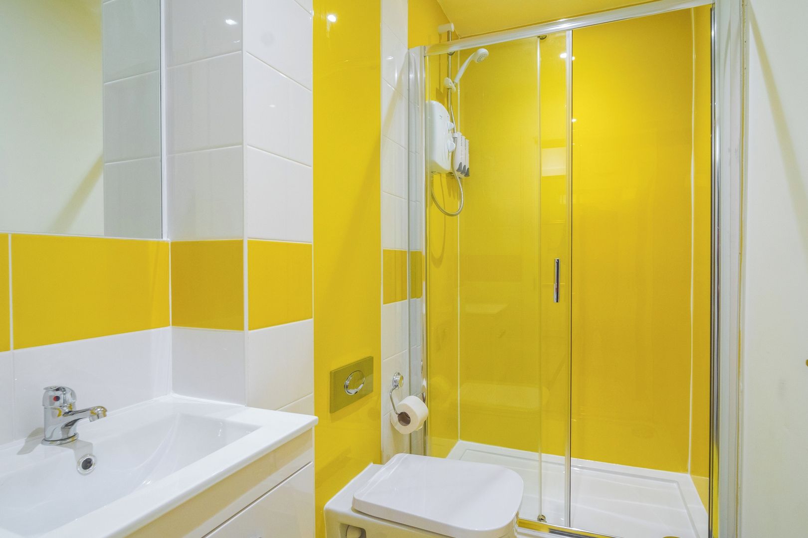 A bathroom with a shower enclosure, a sink, and a toilet.