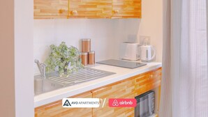 A modern kitchen with wooden cabinets, a sink, a coffee maker, and a kettle. There is a plant on the counter and a tablet. - Creative Studio With Rustic Charm – APT 22 (Sheffield)