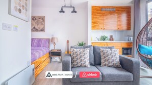 A modern apartment with a bed, sofa, kitchenette, and a hanging chair. - Creative Studio With Rustic Charm – APT 22 (Sheffield)