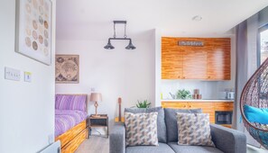 A modern apartment with a bed, sofa, kitchenette, and a hanging chair. - Creative Studio With Rustic Charm – APT 22 (Sheffield)