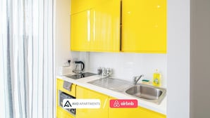 A modern kitchen with yellow cabinets, a sink, a kettle, and a toaster.