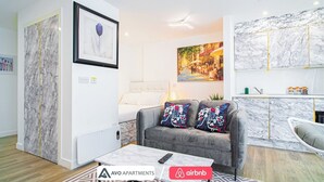A modern living room with a grey sofa, a coffee table, and a painting on the wall. - Stylish Central Studio With Hanging Chair – APT 2 (Sheffield)