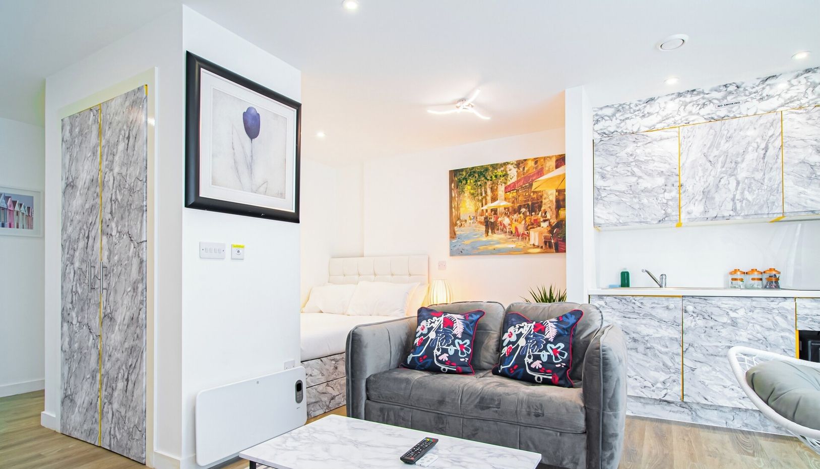 A modern living room with a grey sofa, a coffee table, and a painting on the wall.