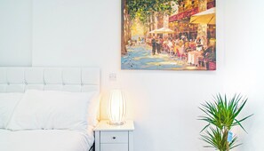 A bedroom with a bed, bedside table, lamp, and a potted plant. - Stylish Central Studio With Hanging Chair – APT 2 (Sheffield)