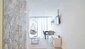 A modern living room with a hanging chair, a dining area, and a small desk. - Stylish Central Studio With Hanging Chair – APT 2 (Sheffield)