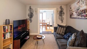A living room with a TV, bookshelf, and a couch. - Luxurious Sheffield Villa 3bed with Stunning Views (Sheffield)