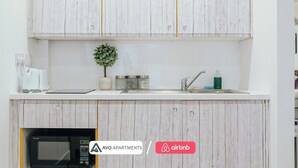 A modern kitchen with wooden cabinets, a built-in microwave, a small potted plant, and a sink with a faucet. - Modern Sheffield Studio With WiFi – APT 15 (Sheffield)