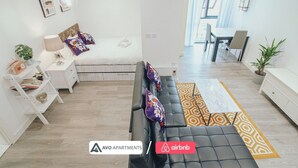 A modern apartment with a sofa, a dining area, and a kitchen visible in the background. - Modern Sheffield Studio With WiFi – APT 15 (Sheffield)