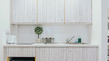 A modern kitchen with wooden cabinets, a built-in microwave, a small potted plant, and a sink with a faucet.