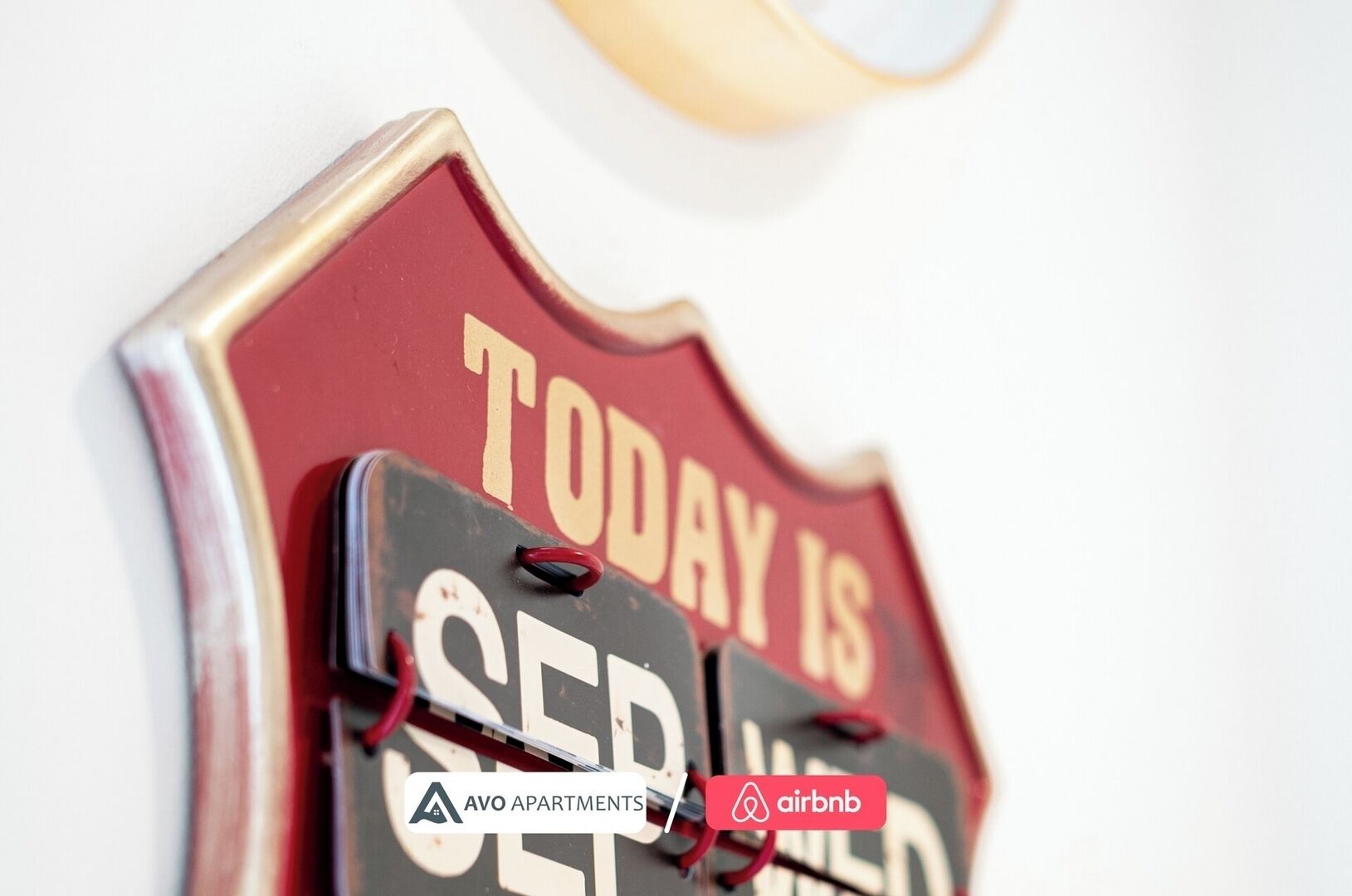 A wall-mounted sign with the text 'TODAY IS SERIOUSLY OPEN' and logos for AVO APARTMENTS and Airbnb.