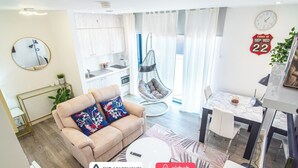 Un salon moderne comprenant un canapé, un fauteuil suspendu, un coin repas et une cuisine.