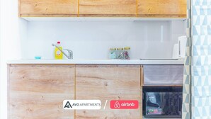 A kitchen with wooden cabinets, a white countertop, a sink, and a microwave. There are jars on the counter and a dish soap bottle. - Eclectic Studio in Central Sheffield – APT 3 (Sheffield)