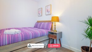A bedroom with a bed, a nightstand, a lamp, and a potted plant. - Eclectic Studio in Central Sheffield – APT 3 (Sheffield)