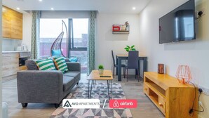 A modern apartment with a grey sofa, dining table, and TV. - Eclectic Studio in Central Sheffield – APT 3 (Sheffield)