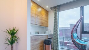 A modern living room with a wooden wall, a hanging chair, a potted plant, and a trash bin. - Eclectic Studio in Central Sheffield – APT 3 (Sheffield)