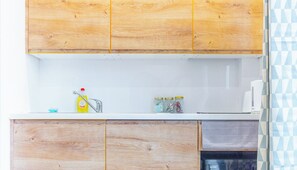A kitchen with wooden cabinets, a white countertop, a sink, and a microwave. There are jars on the counter and a dish soap bottle.