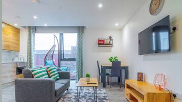 A modern apartment with a grey sofa, dining table, and TV.