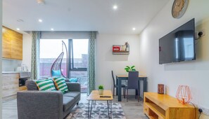 A modern apartment with a grey sofa, dining table, and TV.