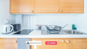 Een moderne keuken met houten kastjes, een inbouwoven, een waterkoker, een broodrooster en een spoelbak met een afwasschaal.