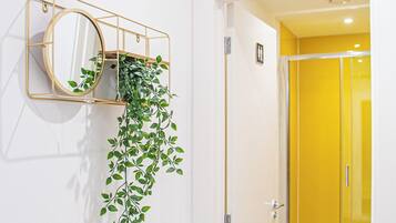 Et vægmonteret spejl med en hængende plante, en gul dør og et skilt for AVO APARTMENTS og Airbnb.