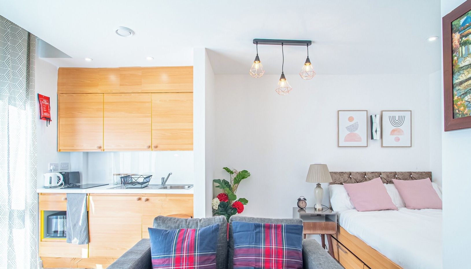 A modern apartment with a kitchen, a dining area, a living room with a sofa, and a bedroom with a bed and nightstand.