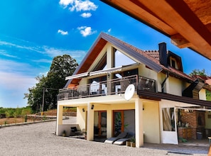 Ein zweistöckiges Haus mit Balkon, Satellitenschüssel und kleiner Sitzgelegenheit im Freien.