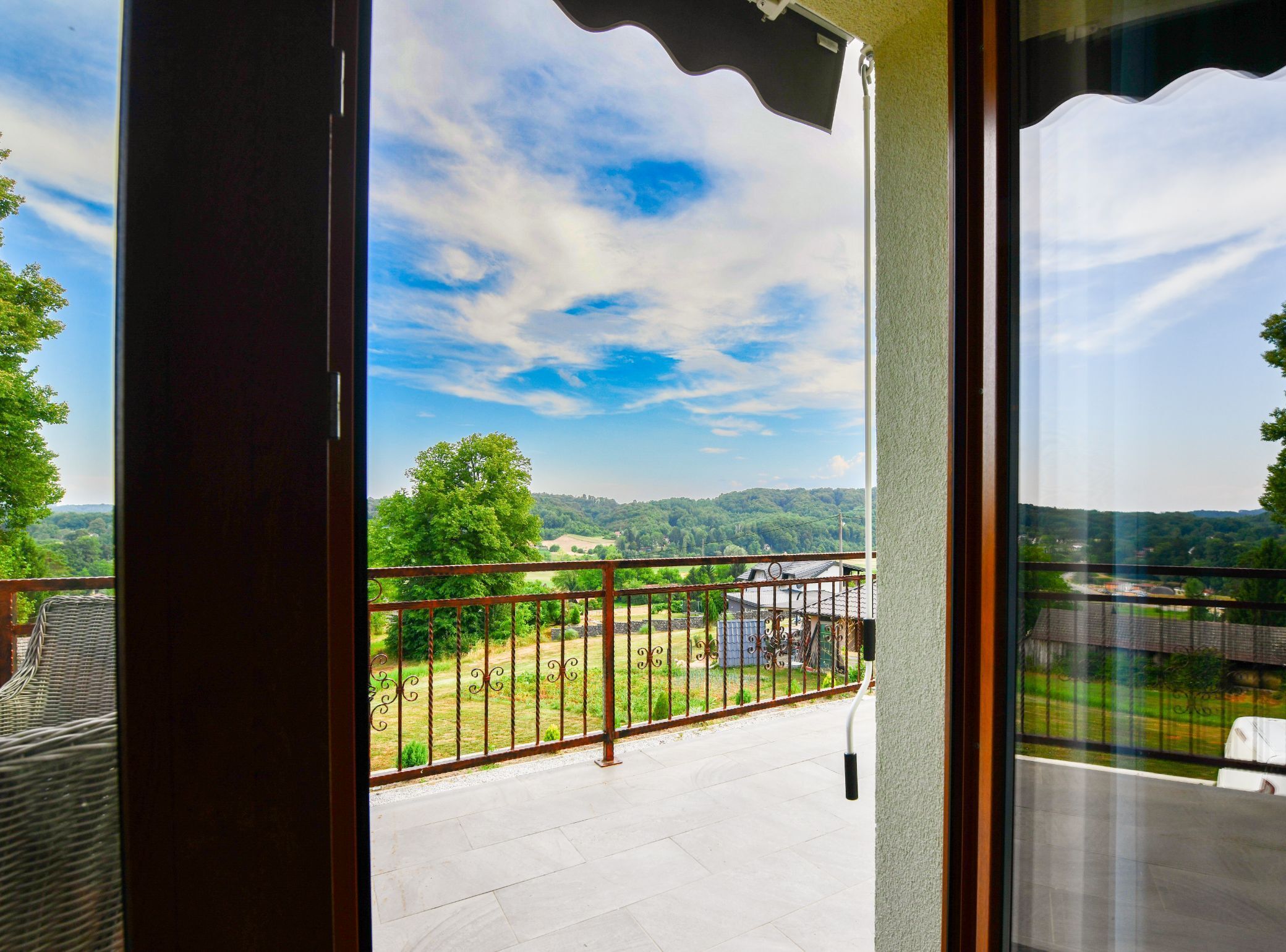 Un balcón con vistas a un paisaje verde y un cielo despejado.