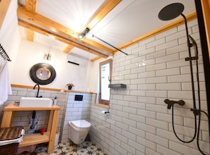 Ein kleines Badezimmer mit Dusche, Toilette, Waschbecken und einer Ablage für Toilettenartikel.