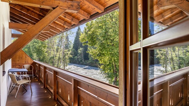 A wooden deck with a view of a river and forest.