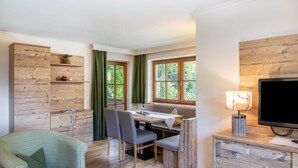 A room with a dining table, chairs, a television, and a wooden cabinet.
