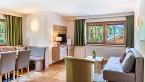 A cozy room with a dining table, chairs, a sofa, a television, and a fireplace.