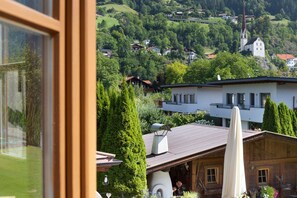 Une vue d’un village perché sur une colline, avec des maisons, une église et un bâtiment en bois surmonté d’un parasol.