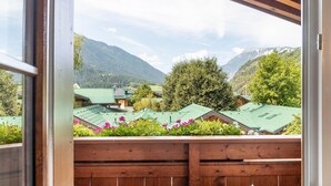 A wooden balcony with a view of houses and mountains.